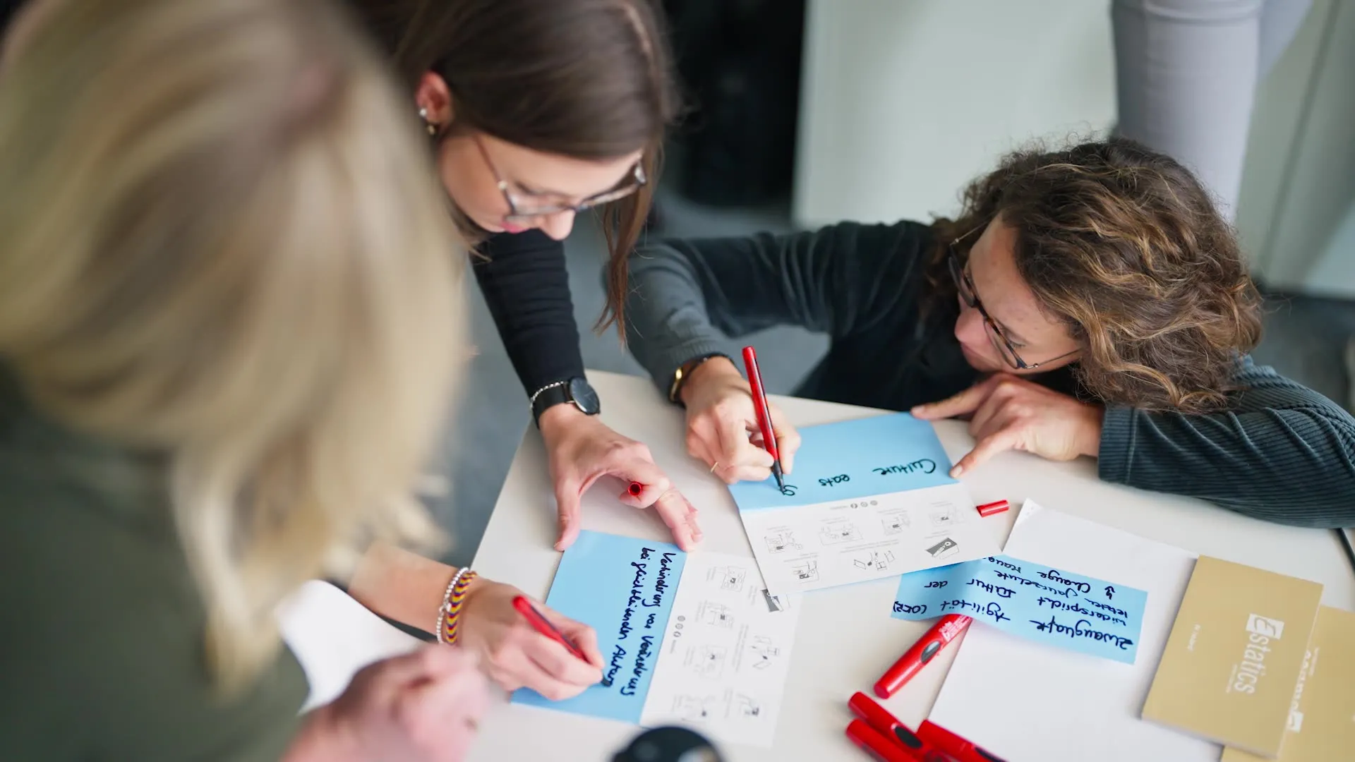 Bei einem Firmen-Workshop beschriften Mitarbeiter verschiedene Zettel für eine Präsentation