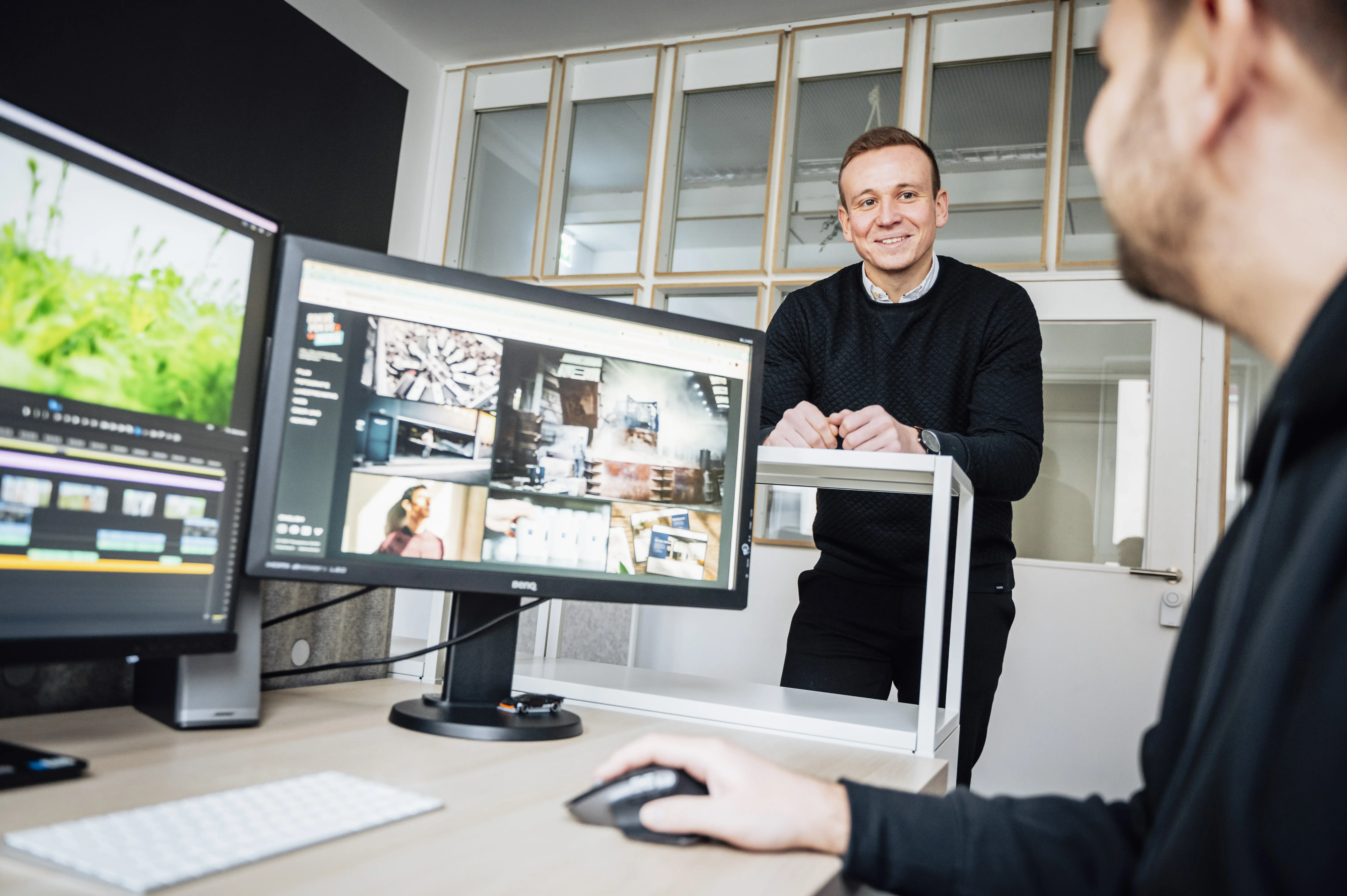 Mitarbeiter unserer Postproduktion in Hannover im Gespräch vor Computermonitoren